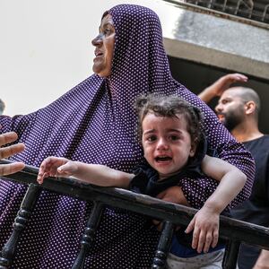 A baby cries as people leave their houses due to the Israeli airstrikes that has been going on for five days at the Sheikh Ridvan neighbourhood of Gaza City