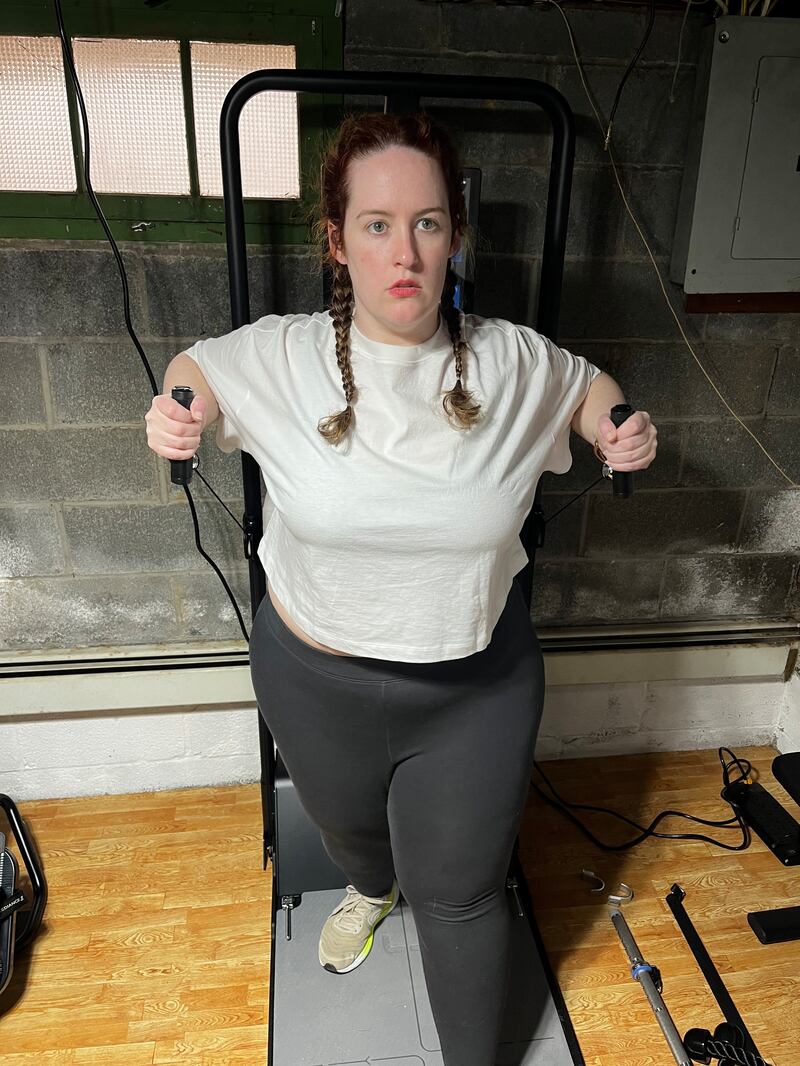 Woman with two French braids wearing gray leggings and white T-shirt working out on the Speediance Gym Monster 2.