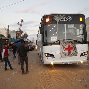 Palestinian youths watch as a bus bearing the emblem of the International Red Cross moves towards the eastern Gaza Strip from Khan Yunis in the south of the besieged territory on October 13, 2025, ahead of the release of Israeli hostages held by Hamas since the October 7 attacks two years ago. On the other side, a Red Cross convoy is on its way to pick up a first batch of Israeli hostages to be freed by Hamas as part of a Gaza ceasefire deal announced by US President Donald Trump earlier this month, the Israeli military said on October 13.