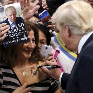 Republican presidential candidate Donald Trump (R) autographs the chest of a woman at his campaign rally in Manassas, Virginia December 2, 2015.  Republican presidential front-runner Trump said on Wednesday his plan for combating Islamic State militants involves targeting not just the group's fighters but also their families.